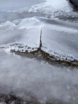 Close Up of Thick Cracked Ice Sheet Over Shallow Water in Winter 스톡 사진