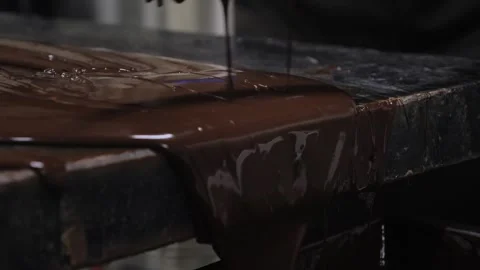 Close-up of thick melted dark chocolate being scraped off marble table with Stock Footage 327789495