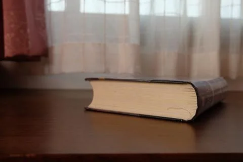 Close up of Thick old book that place on a table near to the window Stock Photos