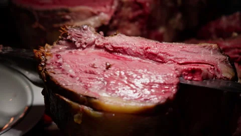 Close-up of thick roast beef being sliced with a long knife and steak fork Stock Footage 282766760