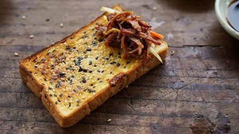 Close-up of a thick slice of toasted bread topped with caramelized onions and Stock Photos