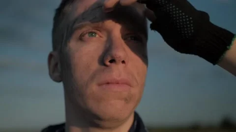 Close up thin dirty guy looking at the sunset into the distance and squints Stock Footage 137845435