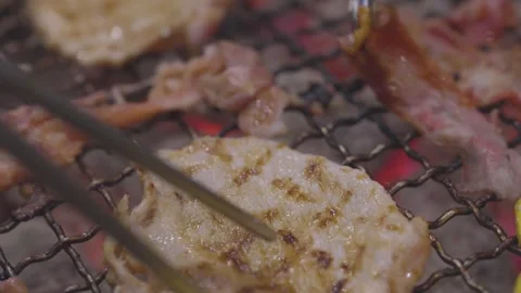 Close-up of thin marinated meat slices grilling on a wire mesh over hot bur.. Stock Footage 336700605