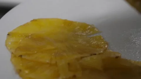 Close-up of thin, translucent dried pineapple slices being prepared on a white s Stock Footage 332811834