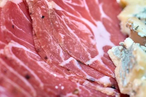 Close-up of thinly sliced cured ham and blue cheese on a gourmet platter Stock Photos