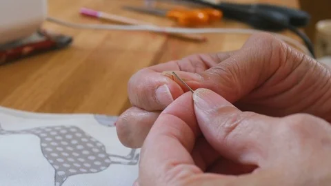 Close up of thread being pushed through the eye of a needle Stock Footage 77113225