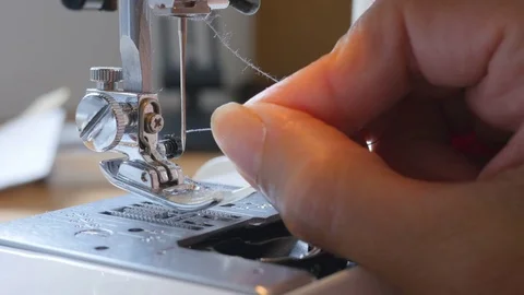 Close of up thread being put through the eye of a needle on sewing machine Stock Footage 77852121