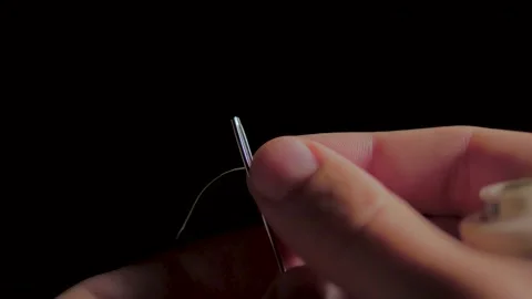 Close-up of a thread that is threaded through the eye of a needle. Stock Footage 149058171