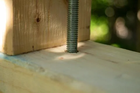 Close-up of a threaded metal bolt inserted through a wooden construction beam 库存照片