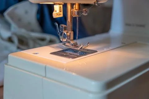 Close up of threaded needle of a sewing machine with material in the background Foto stock