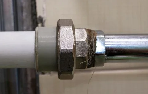 Close up of threaded pipe joint with metal nut and plastic fitting in plumb.. Stock Photos