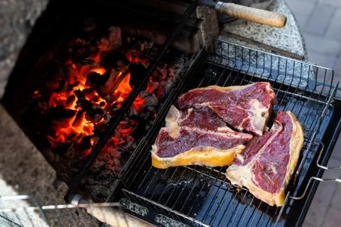 Close-up three big tasty juice raw t-bone beaf steak on grill at barbecue with Stock Photos