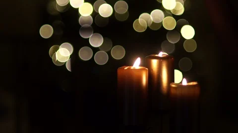 Close-up of three candles on a dark background with Christmas lights. Two Stock Footage 97563592