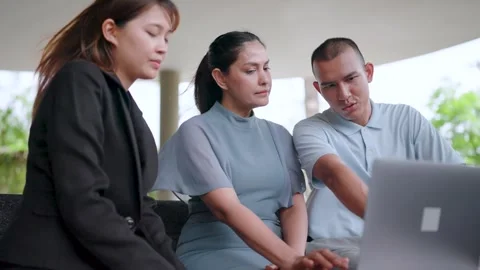 Close-up of three co-worker freelancers sitting at a table with laptops  Stock Footage 265735716