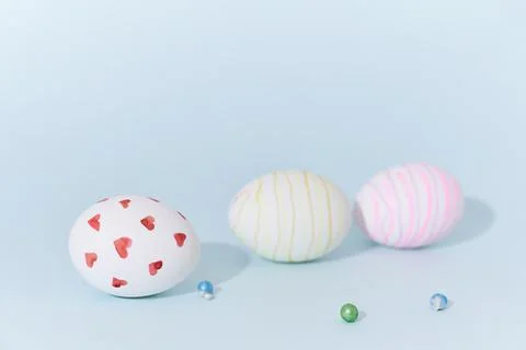Close-up of three Easter eggs with a pattern of hearts and lines on a blue Stock Photos