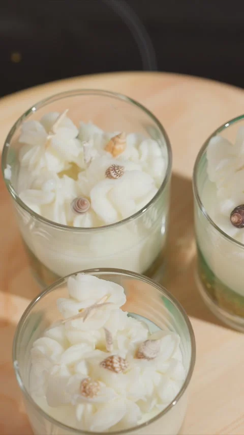 Close up of three glass candles with white whipped wax and seashell decorations Video stock 344677692
