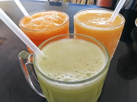 Close-up of three glasses of freshly squeezed juice with tubes. Delicious, nu Foto stock