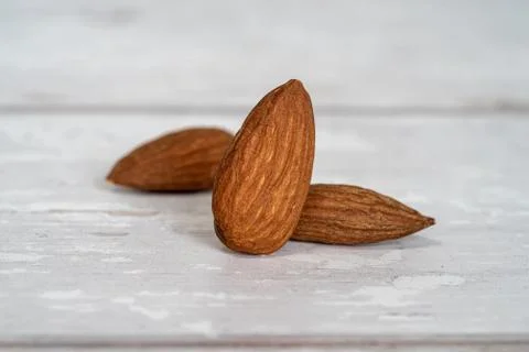 Close-up of three isolated almonds standing up on a wooden table Stock Photos