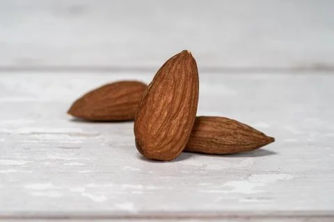 Close-up of three isolated almonds standing up on a wooden table Stock Photos