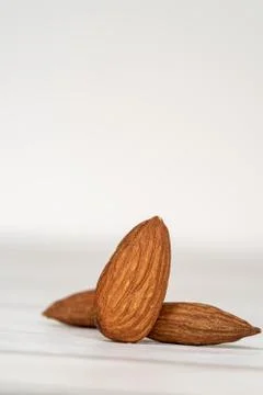 Close-up of three isolated almonds standing up on a wooden table Stock Photos