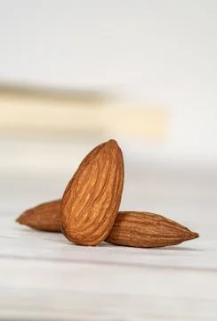 Close-up of three isolated almonds standing up on a wooden table Foto stock