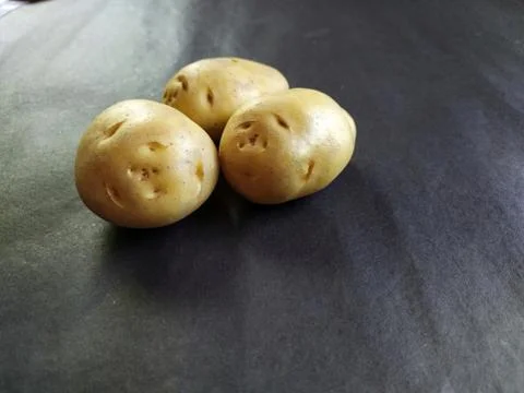 Close up of three potatoes on dark work desk Stock Photos