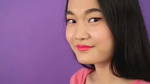Close-up three quarter portrait of young asian woman on isolated purple Stock Footage 144818157