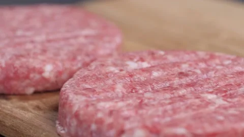 Close up. Three raw burger patties lying on a wooden board. Video stock 228648951
