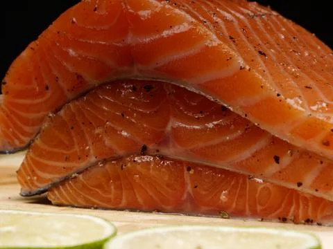 A close-up of three slices of fresh raw red salmon fillets which lie on top Stock Photos