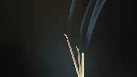 Close up of three smoldering incense, white light from below, upward camera Stock Footage 313439127