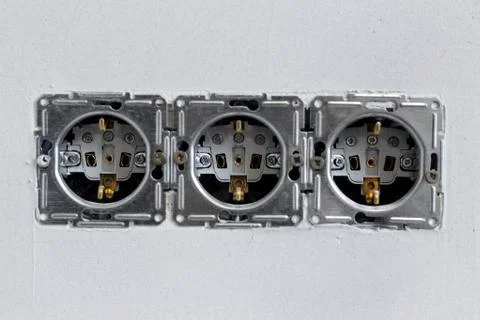 Close-up of three sockets on background of grey wall. Stock Photos