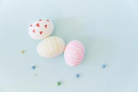 Close-up of three white Easter eggs with a pattern of hearts and waves on a blue Foto stock