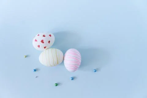 Close-up of three white Easter eggs with a pattern of hearts and waves on a blue Foto stock