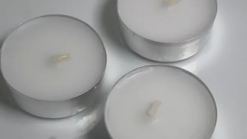Close-up of three white tea light candles in silver aluminum cups on a whit.. Stock Footage 331354489