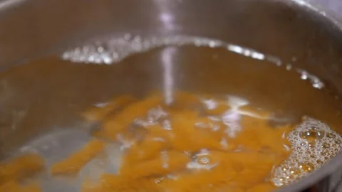 Close up of throwing pasta into boiling water and stirring in a pot Видео 336640142