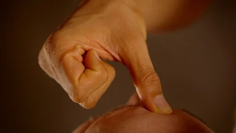 Close-up of the thumb of the palm presses on the chakra at the base of the Stock Footage 105308805