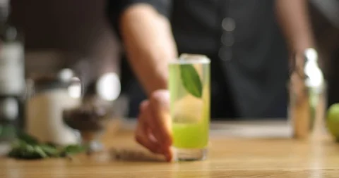 Close-up tight bartender hands a cocktail. green cocktail with bay leaf on the Stock Footage 126153196