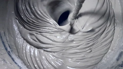 Close up. Tile adhesive is mixed using an electric drill in a bucket Stock Footage 153682421