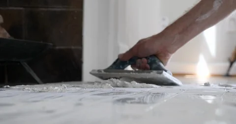 Close-up of a tile setter's hands spreading white grout. Stock Footage 129066473