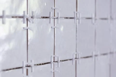A close up of a tile wall under construction. The wall is being tiled with .. Stock Photos