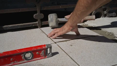 Close-Up of Tiler Adjusting Floor Tiles with Rubber Mallet in Outdoor Job Stock Footage 303210826