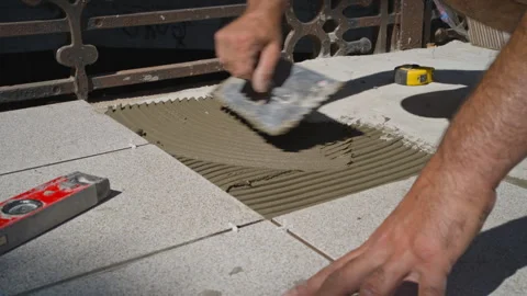Close-Up of Tiler Applying Tile Adhesive on Concrete Floor in Daylight Stock Footage 303210607