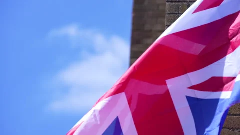 Close-up Tilt-down of Union Jack slowly fluttering round a brick wall Video stock 240514012
