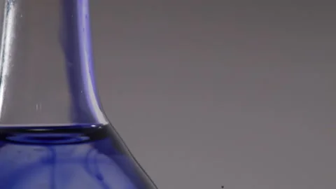 Close up tilt of a flat bottomed flask filled with blue liquid Video stock 231488234