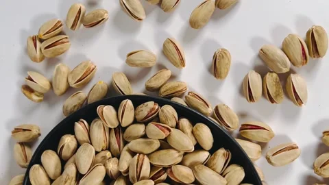 Close-up tilt shot from bottom to top of roasted pistachios on a black plate Vídeos de archivo 336136458