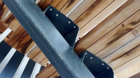 Close-up of timber ceiling slats with black steel brackets, screws and a grey Stock Footage 338004348