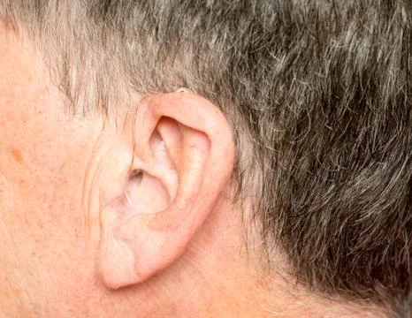 Close up of a tiny modern hearing aid behind ear Stock Photos