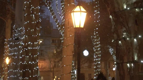 CLOSE UP: Tiny snowflakes start falling from the sky and past a lit up lantern. Stock Footage 120186137