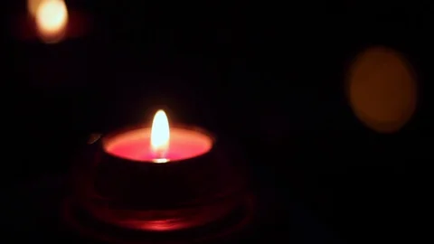 Close up of a tiny tea light candle in darkness being blown up with the Stock Footage 128321782