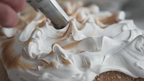 Close up on tip of pastry torch roasting meringue, natural light, slow motion Stock Footage 240934360